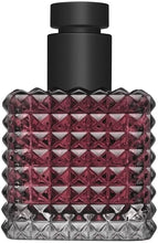 Perfume bottle with black cap and red geometric pattern on a white background