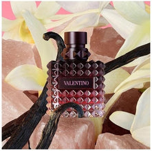 Valentino perfume bottle with vanilla beans and flowers in the background